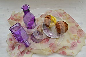 Chocolate cupcakes on a dessert table with vintage shawl and purple bottles