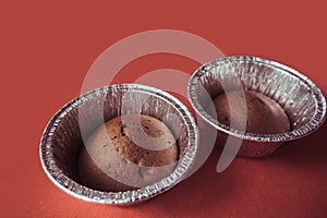 Chocolate cupcakes in foil baking dish on Marsala background. Brown muffins in foiled baking forms