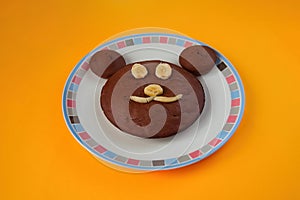 Chocolate cupcakes in the shape of a bear with banana on a plate on table. Cake with eyes, nose and mouth made from banana.