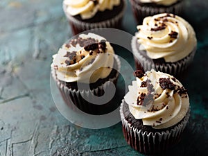 Chocolate cupcakes with whipped cream garnished with grated dark chocolate on a green marble background. Close-up. Lots of objects
