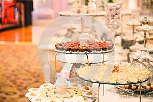 CHOCOLATE DESSERT WITH A CHERRY ON TOP IN A STRAIGHT ARRANGEMENT FOR A WEDDING DESSERT TABLE FULL OF CANDY AND PASTRY