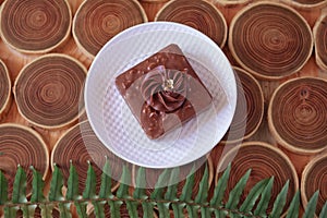 chocolate dessert with filling of caramel, nuts and nougats. The cake is covered with chocolate on a wooded background