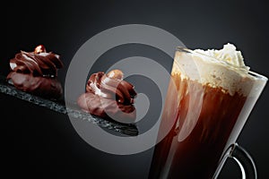 Chocolate dessert with hazelnut and coffee with cream on a black background