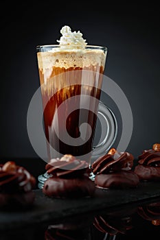 Chocolate dessert with hazelnut and coffee with cream on a black background