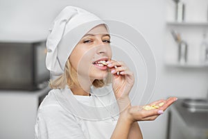 Chocolate desserts, chocolate drops, sweets. Close up portrait of young female confectioner, enjoying her work in pastry