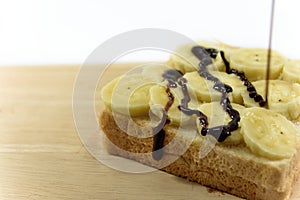The chocolate dip is a fresh on bnanas and bread slice placed on the wooden board.