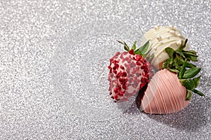 Chocolate dipped strawberries on shiny silver background