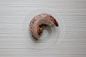 A chocolate donut being eaten and placed on a table from breakfast