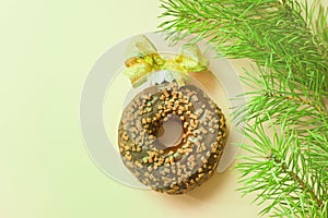 chocolate donut with golden bow like christmas ball near fir tree. glazed ball top view from above