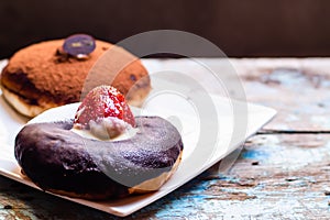 Chocolate donut with strawberry with blue painted wooden table background