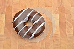 Chocolate donut with stripes on wooden table. Sweets. Selective