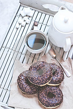 Chocolate donuts and coffee , weekend morning table. Breakfast on a wooden tray. Vintage colors.