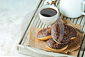 Chocolate donuts and coffee , weekend morning table. Breakfast on a wooden tray. Vintage colors.