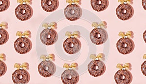 chocolate donuts pattern with golden bows on pink background. christmas glazed decorations -top view