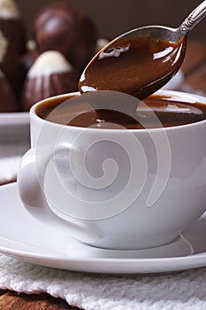 Chocolate dripping from a spoon in a cup closeup