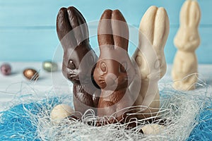 Chocolate Easter bunnies and eggs in decorative nest, closeup