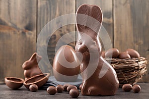 Chocolate Easter bunny, eggs and sweets on rustic background