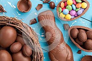 Chocolate Easter bunny, eggs and sweets on rustic background