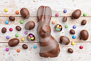 Chocolate Easter bunny, eggs and sweets on rustic background