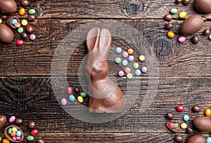 Chocolate Easter bunny, eggs and sweets on rustic background