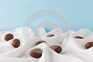 Chocolate Easter eggs in gauze fabric folds and cyan background