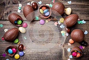 Chocolate easter eggs and sweets on wooden background