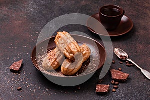 Chocolate eclair and coffee cup on dark background