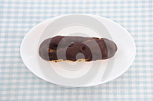 Chocolate eclair cream puff on plate on table