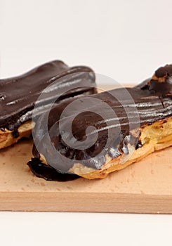 Chocolate eclair on wooden desk food photography. Bekery, cake , choco, pie, confectionary, cream. Three fresh eclairs with chocol