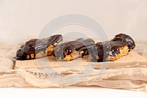 Chocolate eclair on wooden desk food photography. Bekery, cake , choco, pie, confectionary, cream. Three fresh eclairs with chocol