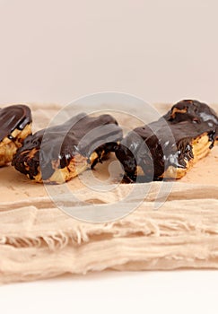 Chocolate eclair on wooden desk food photography. Bekery, cake , choco, pie, confectionary, cream. Three fresh eclairs with chocol