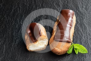 Chocolate eclairs on black stone background