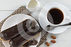 Chocolate eclairs with coffee and milk. Chocolate eclairs on plate with coffeel sweet breakfast. Cafe menu