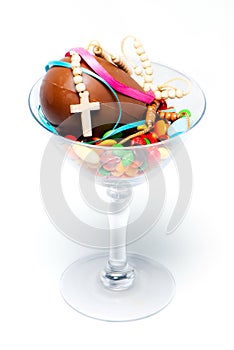 Chocolate egg , sweets and cross in a glass