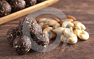 Chocolate Energy Protien Balls Made of Raw Organic Nuts and Dates on a Wooden table