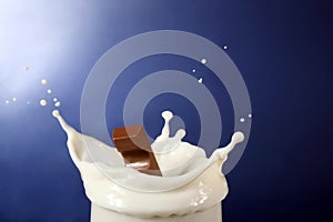 Chocolate falling into milk on blue background