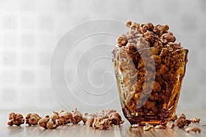 Chocolate flavored popcorn in the yellow glass and on the brown wood table with cinnamon background