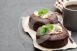 Chocolate fondant with almonds and cup of coffee on black stone