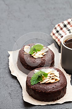 Chocolate fondant with almonds and cup of coffee on black stone background