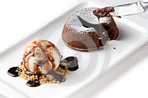 Chocolate fondant and a scoop of ice cream in a white plate on an isolated white background closeup