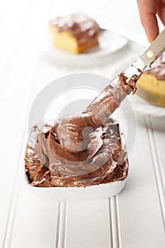 Chocolate frosting with slice of yellow cake with spreading knife