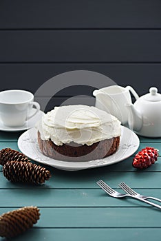 Chocolate fruit cake with cream cheese and black tea decorated with cones on dark background