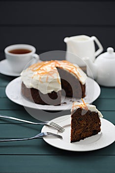 Chocolate fruit cake with cream cheese glasing and orange peel served with black tea on dark background