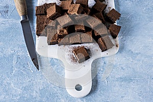 Chocolate ganache truffle squares dusted with cacao being cut into cubes