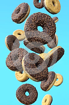Chocolate glazed doughnuts in motion against blue background.