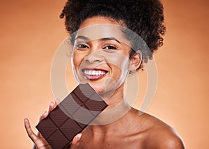 Chocolate, happy woman and beauty portrait on studio background eating sweets, dessert or sugar. Young african american