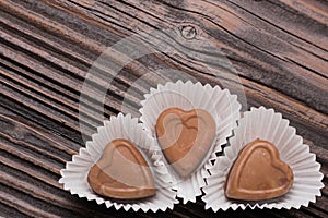 Chocolate heart-shaped candy on wooden background