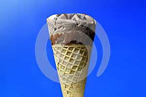 Chocolate ice cream cone on blue background