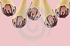 Chocolate ice cream in crisp waffle cones with sweet brown sauce as decorative frame on pink background.