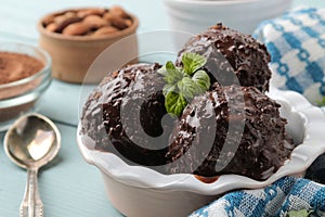 Chocolate ice cream with liquid chocolate and with a cinnamon stick, coffee beans and almonds on a blue wooden background